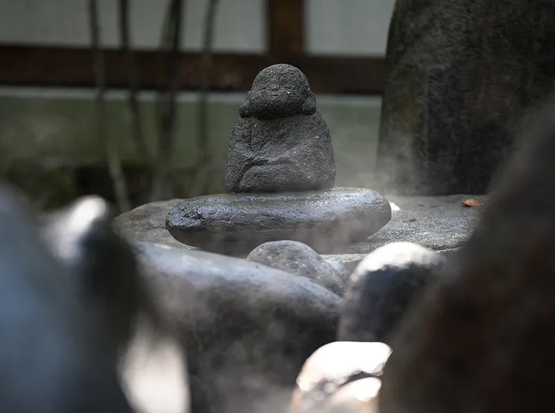 穏やかな表情の見守り地蔵が露天風呂のどこかに